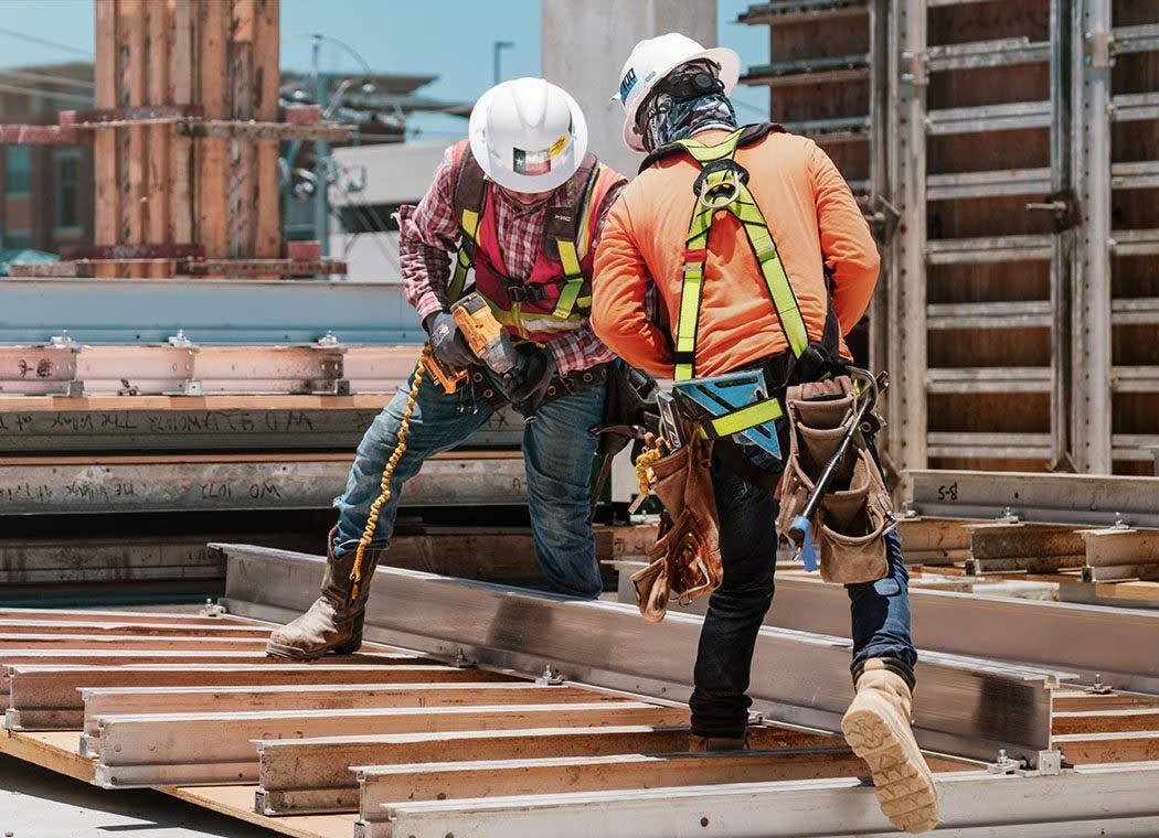 Construction workers drilling on a roof