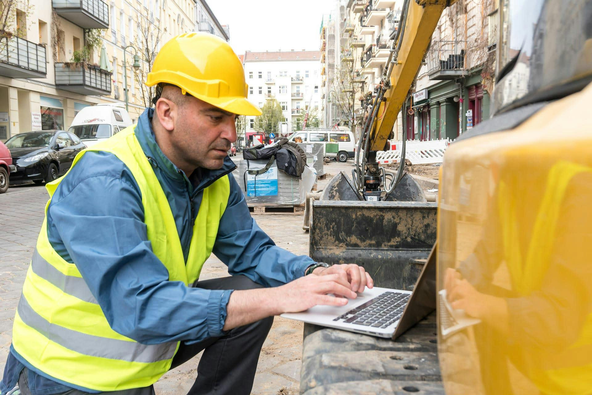 Construction worker on site using Procore on a laptop