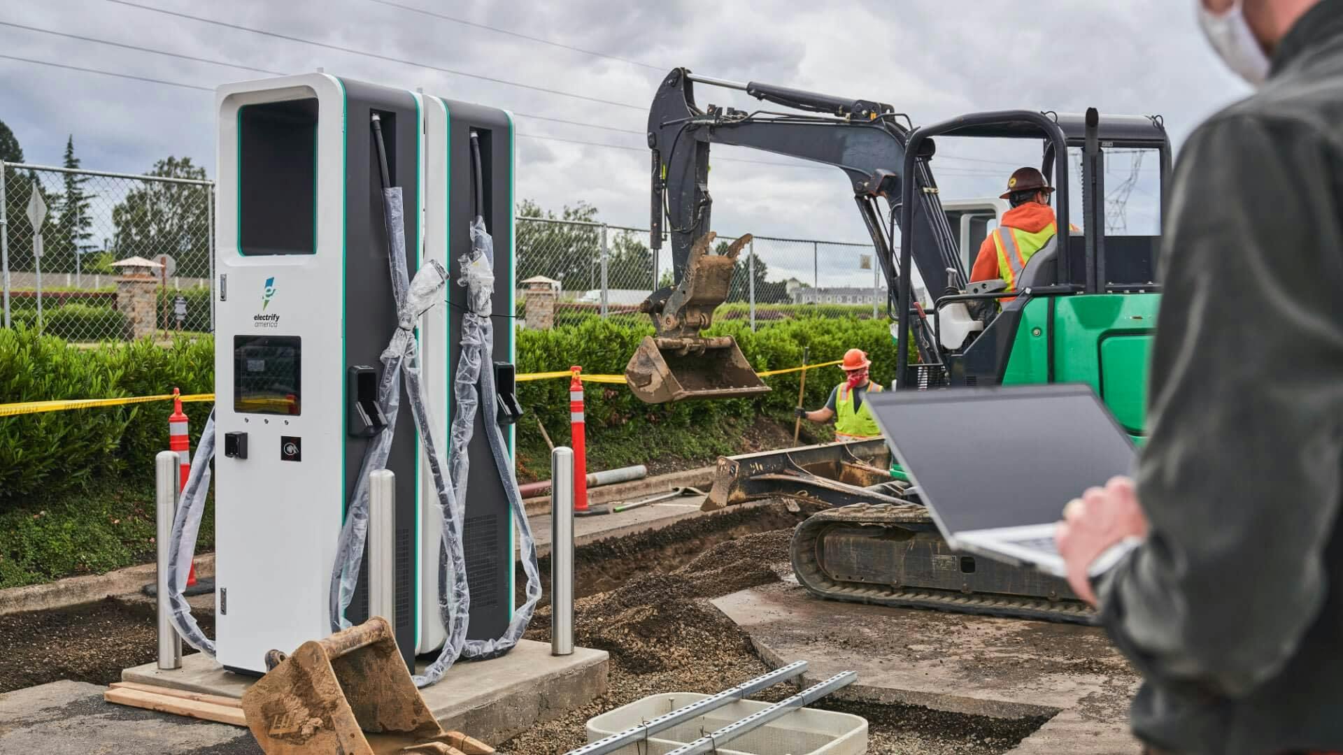 Workers installing electric car chargers with heavy machinery