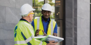 Photo of 2 construction workers in PPE having a discussion over paperwork