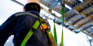 Close up of person's back with safety harness strapped to scaffolding.