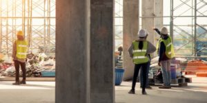 Construction workers standing on jobsite looking up at scaffolding.