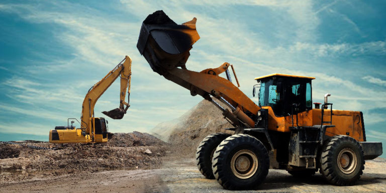 Front loader lifts its bucket in front of mounds of soil.
