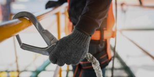 Close up of construction worker's hand clipping a rope to a railing.