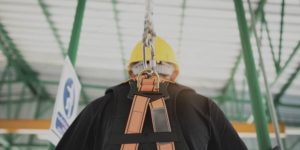 Construction worker wearing a harness clipped to a rope.