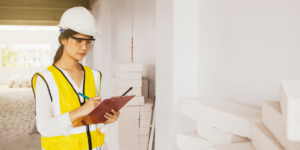 Photo of a contractor holding a clip board with a punch list on a construction site