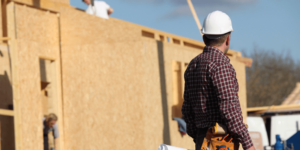 Photo of a construction worker on a job site wearing a hardhat and walking away from the camera