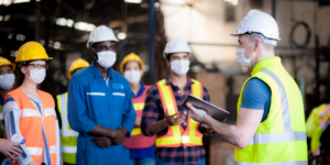 Photo of a person conducting a construction safety review, all workers in the photo are wearing personal protective equipment