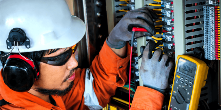 Photo of electrician wearing PPE working on electrical panel.