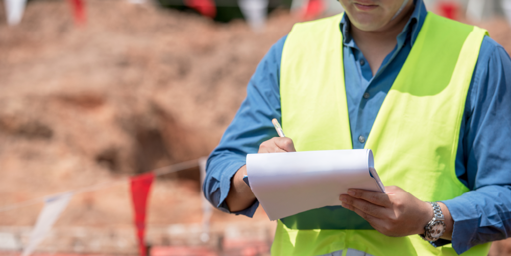 Closeup photo of worker in reflective vest conducting construction jobsite inspection