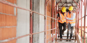 Construction worker helps injured worker walk along scaffolding