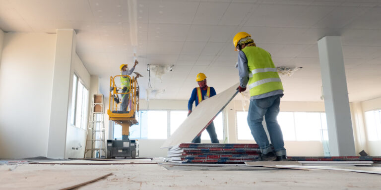 Contractors installing drywall in a commercial building.