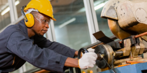 Photo of a worker dealing with construction noise while using a large piece of noisy equipment by wearing the proper PPE, in this case over-ear protection.