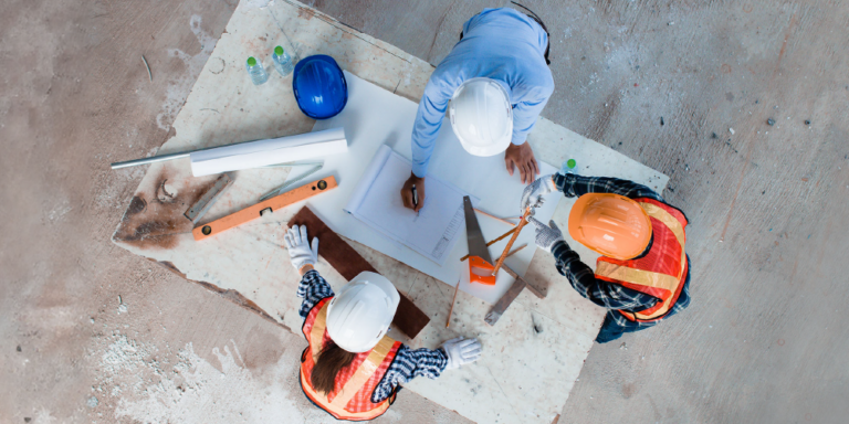 Overhead photo of 3 construction workers looking at design plans