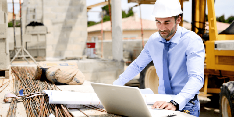 Architect in hard hat looking at MasterFormat specs on laptop