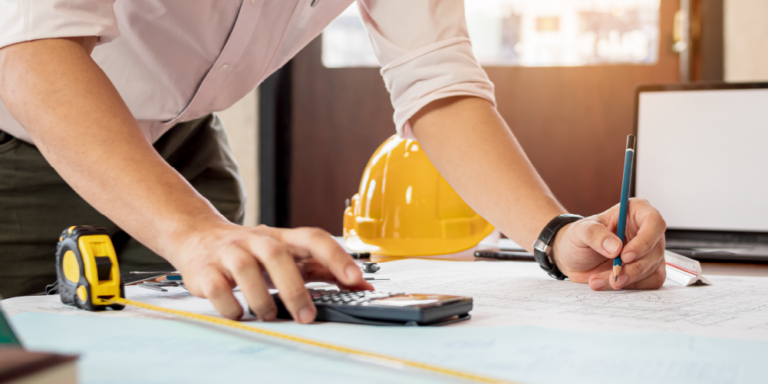 Photo of construction worker looking at calculator