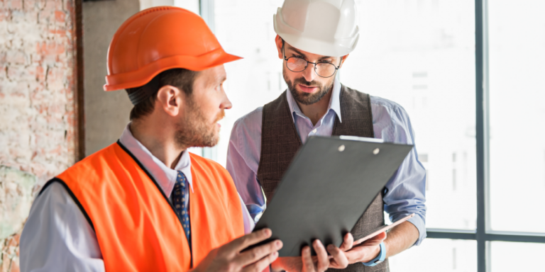 Two contractors review a construction inspection report on a clipboard.