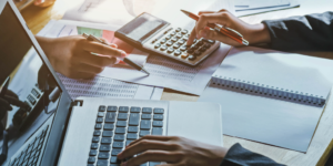 Up close photo of accounting documents, calculator, and laptop