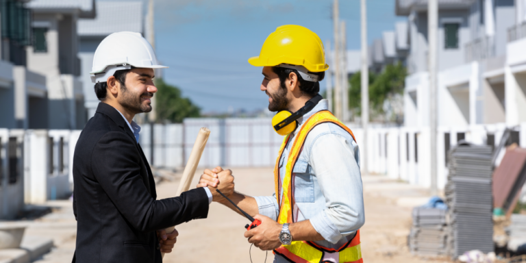 A construction contractor and owner shake hands while on a construction site.