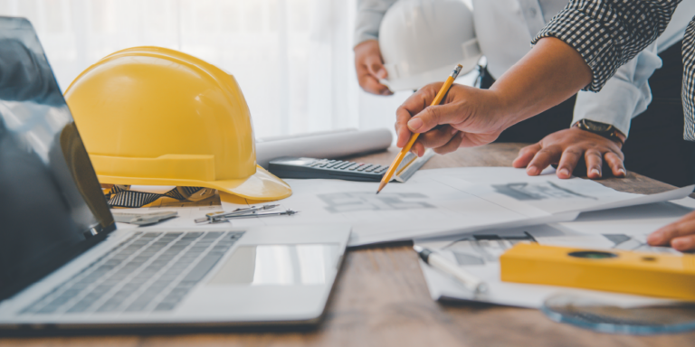 Closeup photo of a construction professional writing notes in front of a laptop