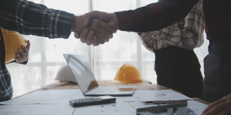 Photo of two unseen people shaking hands over an agreement