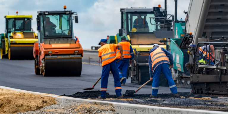 Photo of multiple construction workers engaged in road work construction