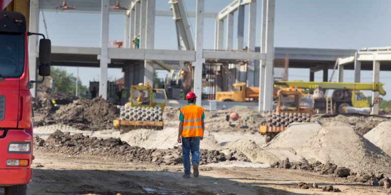 Photo of one construction professional from behind, looking out at a construction site