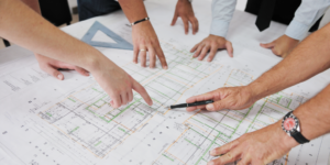 Photo of people's hands as they collaborate over a construction drawing
