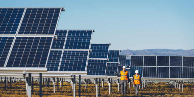 Photo of a solar construction project with 2 workers walking between panels