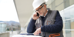 Photo of construction professional on a cell phone while looking at a tablet