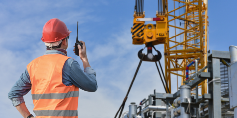 Photo of a construction professional talking on a radio while inspecting a crane