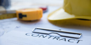 Top of a construction contract document with tape measure and hard hat