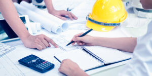 2 people looking at construction financial documents with hard hat on the table