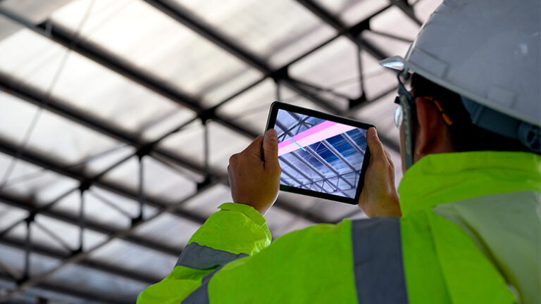 Construction worker comparing a 3D construction model on a tablet to the physical jobsite