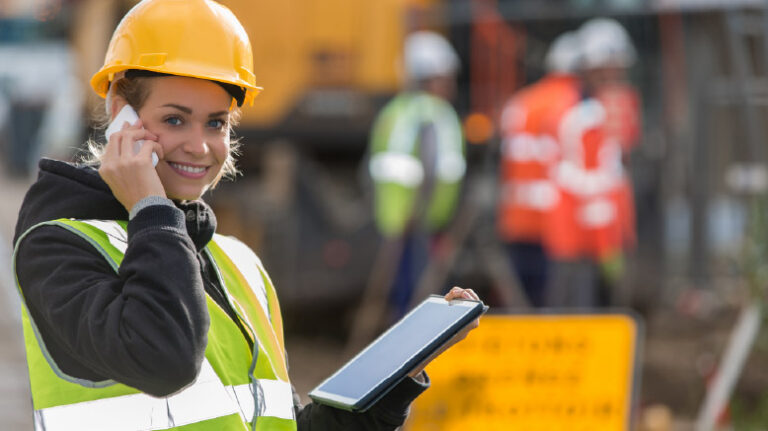 Construction worker looking at a tablet while talking on a cell phone