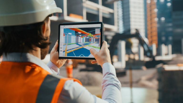 Construction worker comparing a jobsite to a 3D model of the jobsite on a tablet