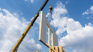 Modular construction panel being put into place by a crane on a construction jobsite