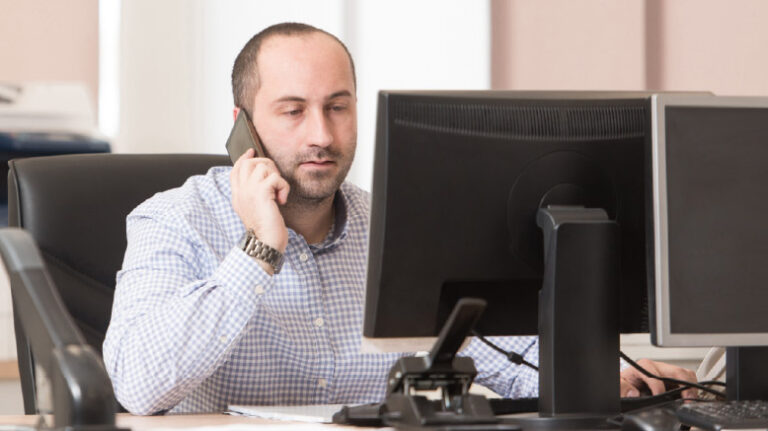 Construction office worker on the phone in front of a computer