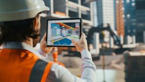 Construction professional holds a tablet comparing a BIM file to the actual jobsite.