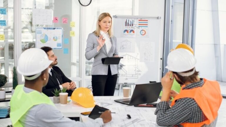 Construction office worker giving a presentation to a group of field workers in PPE