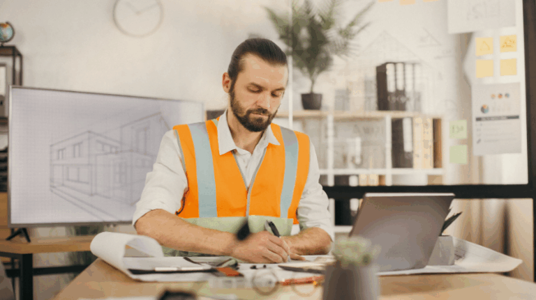 Construction worker in an office looking at a laptop