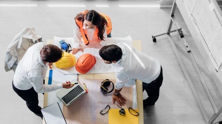 3 construction professionals meeting around a table with drawings