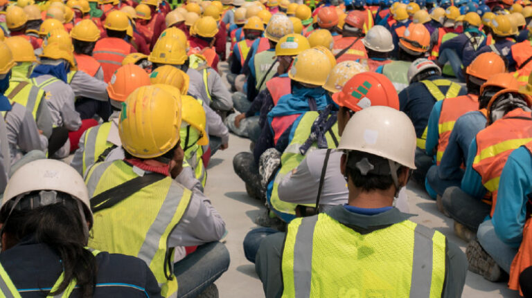 Group of workers in hard hats sitting on the ground