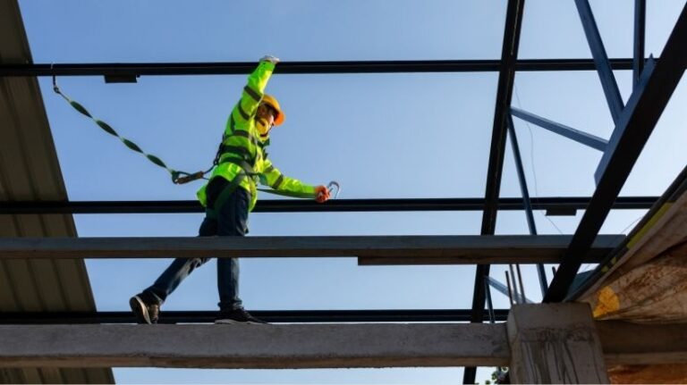 Worker in high-vis gear and a harness conducts a construction site inspection