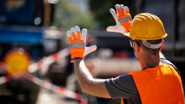Construction worker guiding an equipment driver on a jobsite
