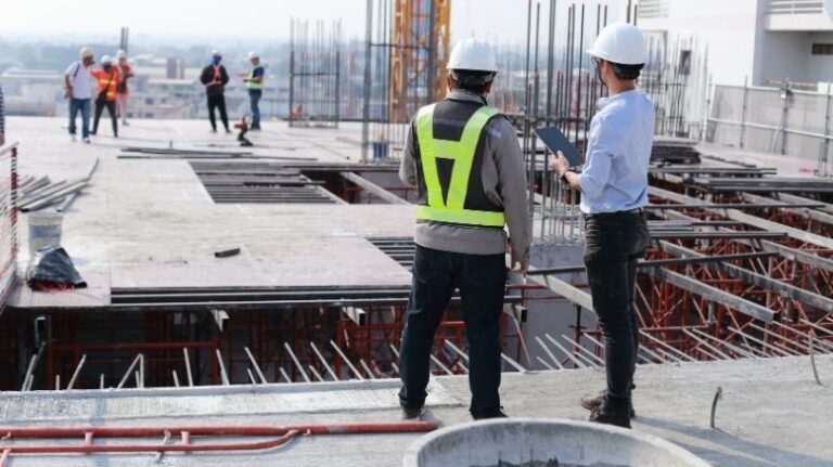Two workers looking at an unfinished floor in a construction site
