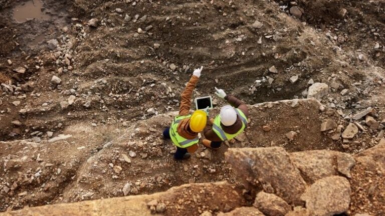 Top-down aerial photo of 2 workers surveying an undeveloped building site during the preconstruction phase
