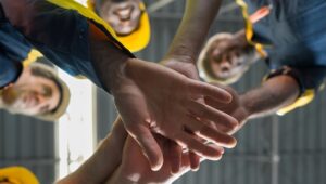 Construction workers put their hands together in camaraderie after a meeting.
