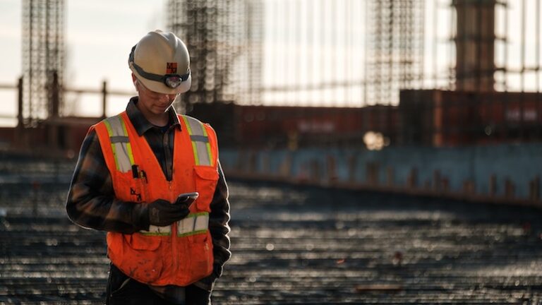 Worker on a jobsite checks a real-time mobile dashboard from the field.