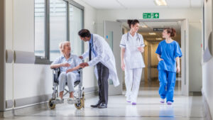 Interior of a hospital hallway with doctors, nurses, and a patient in a wheelchair